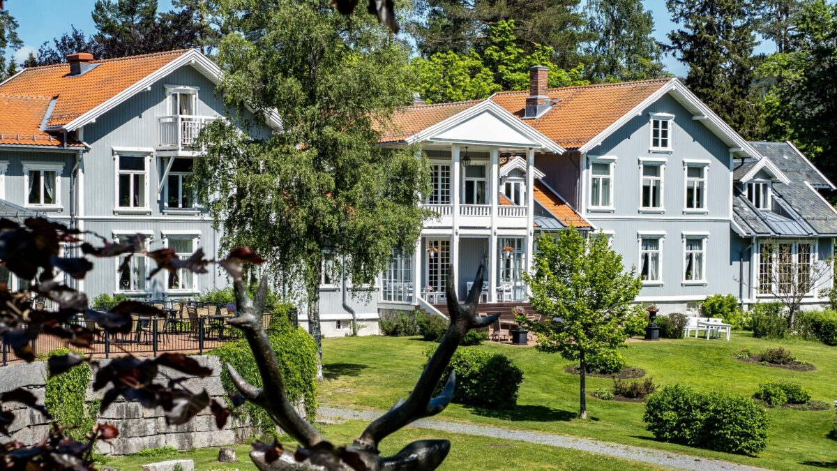 Fronten av Losby Gods. Omgitt av hage og grønne skoger