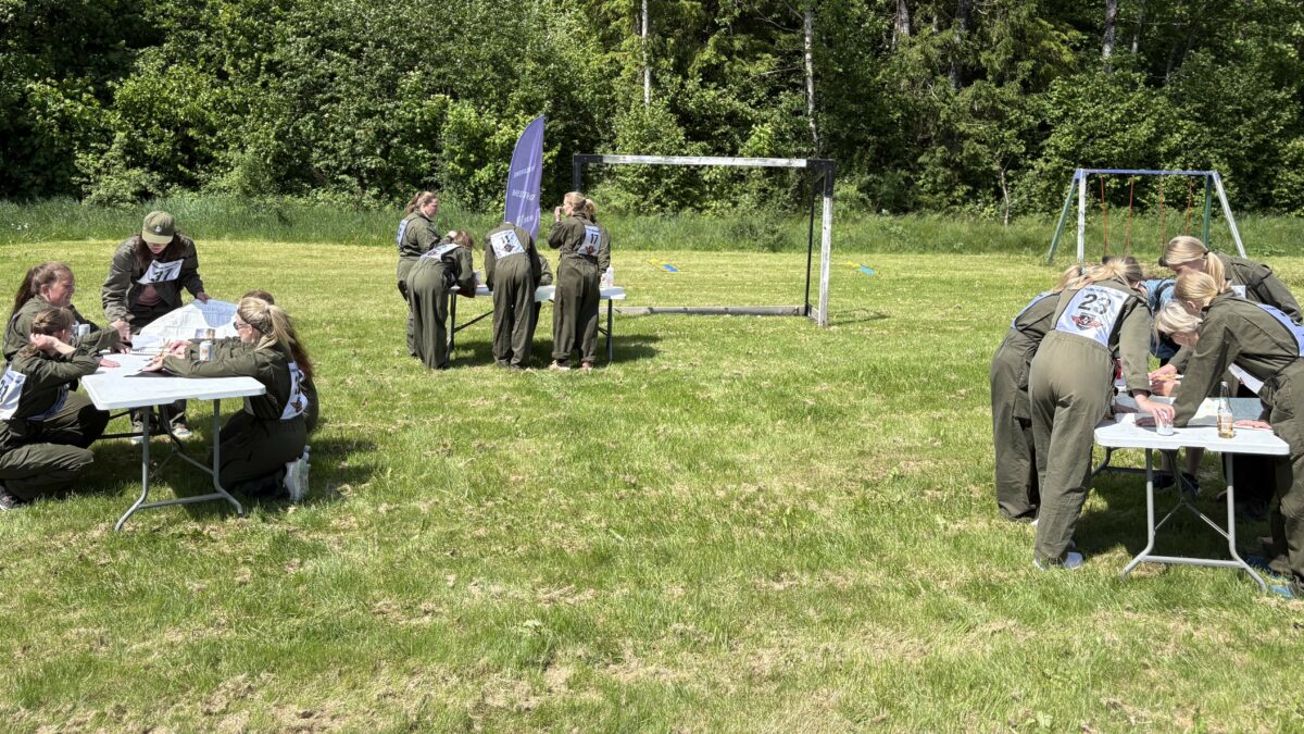 Mennesker i grønne drakter som står bøyd over bord på en grønn gressplen